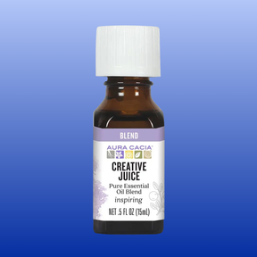 Aura Cacia Creative Juice Essential Oil Blend 0.5 oz bottle with inspiring citrus and spice aroma on blue background