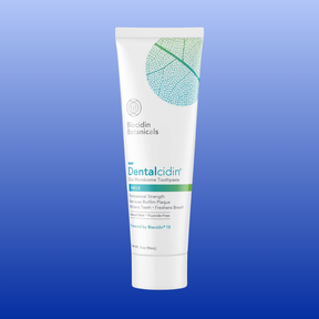 Tube of Dentalcidin Oral Microbiome Toothpaste with botanicals, professional strength, and biofilm plaque removal on blue background