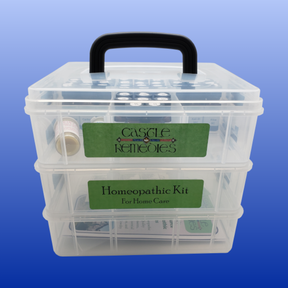 Portable transparent plastic box with black handle holding a homeopathic home care remedy kit with labeled green stickers