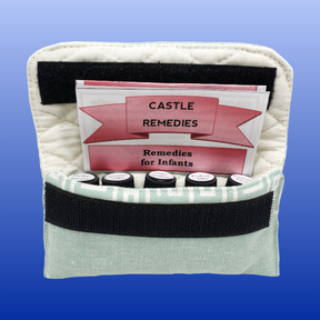 Open textile pouch displaying Castle Remedies Infant Kit with small remedy bottles and an instruction booklet inside.