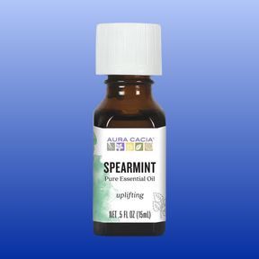 Brown glass bottle of Aura Cacia spearmint pure essential oil with white cap on blue background
