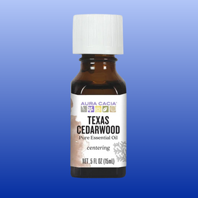 Brown glass bottle of Texas Cedarwood essential oil with white cap on blue gradient background